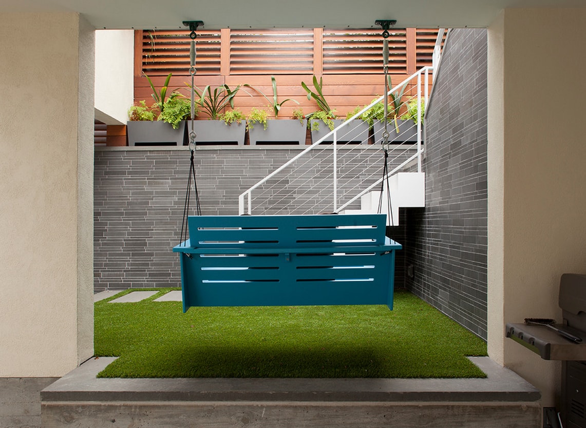 Norstone Grey Basalt Lynia Interlocking Tile Feature Wall in San Francisco Interior Courtyard with Synthetic Turf and a porch swing